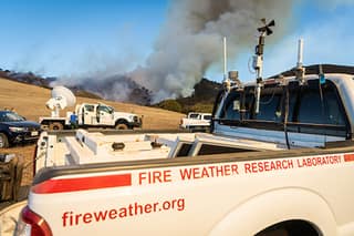 Wildfire research truck sits in front of a burning hillside